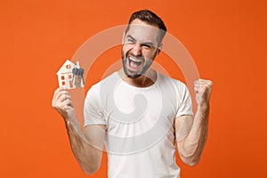 Happy young man in casual white t-shirt posing isolated on orange background studio portrait. People lifestyle concept