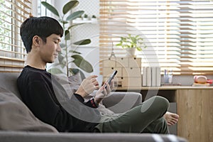 Happy young man checking social media or shopping online on smart phone