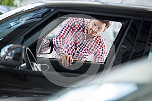 Happy young man chooses to buy a car