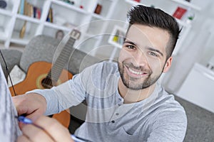 Happy young man composing music with guitar