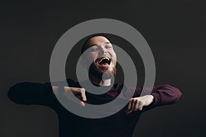 Happy young man dancing on a gray background. bald with a beard