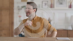 Happy Young Man Dancing while Sitting in Office