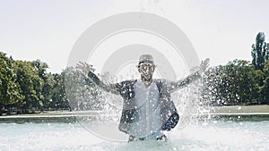 Happy Young Man Dancing in Water Fountain in Summer Time