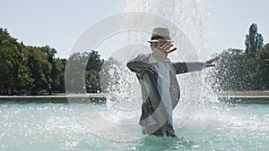 Happy Young Man Dancing in Water Fountain in Summer Time