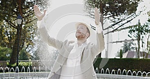 Happy Young Man Dancing in Water Fountain in Summer Time