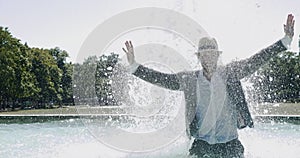 Happy Young Man Dancing in Water Fountain in Summer Time