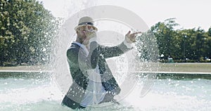 Happy Young Man Dancing in Water Fountain in Summer Time