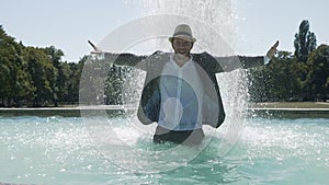 Happy Young Man Dancing in Water Fountain in Summer Time