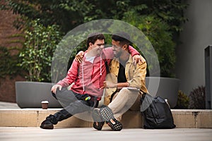 Happy young man with Down syndrome and mentoring friend sittingwith arms around outdoors