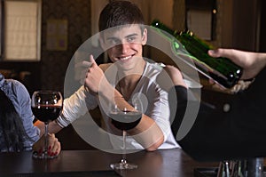 Happy young man drinking wine with friends