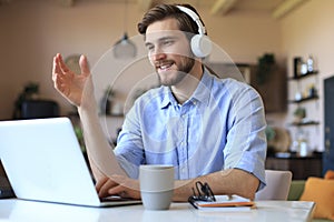 Happy young man in earphones working on laptop from home during self isolation