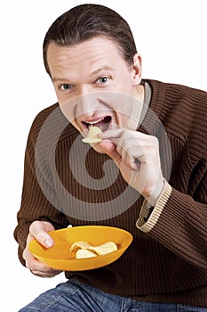 Happy young man eating potato chips