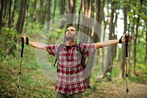 Happy young man enjoying a perfect peaceful moment during hike through forest. Arms outstretched