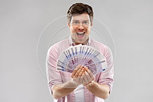 Happy young man with fan of euro money