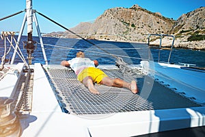 Happy young man feels happy on the luxury sail boat yacht catamaran in turquoise sea in summer holidays on island.