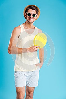 Happy young man in hat and sunglasses holding frisbee disk