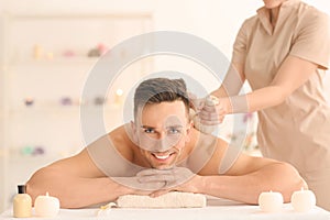 Happy young man having massage in spa salon