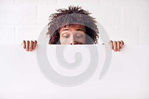 Happy Young Man Holding Blank White Card With Copy Space Standing Against White Studio Wall