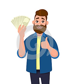 Happy young man holding cash/money/banknotes and showing thumbs up or like sign. Financial money concept. Human emotion concept.