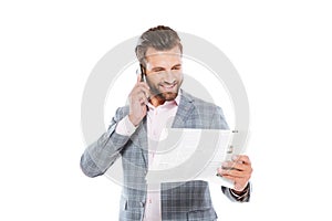 Happy young man holding gazette and talking by mobile phone