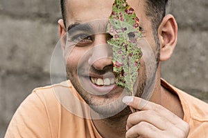Happy young man holding a ruin leaf in front of face at outdoor