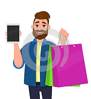 Happy young man holding shopping bags. Person showing blank screen tablet computer in hand. Male character illustration.