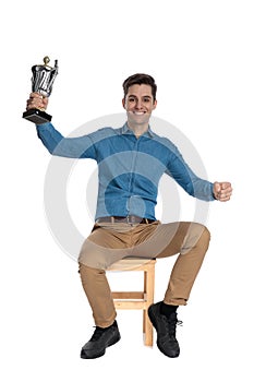 Happy young man holding trophy and celebrating victory