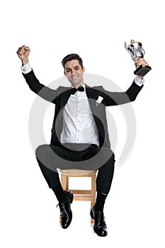 Happy young man holding trophy and celebrating victory