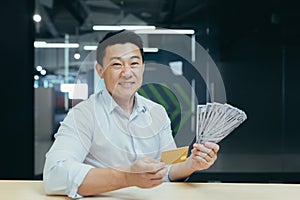 A happy young man holds a credit card and cash money in his hands, received a loan, investment