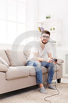 Happy young man at home playing video games