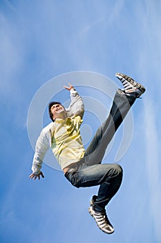Happy young man - jumping end flies in blue sky.
