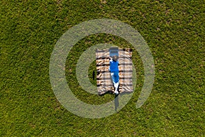 Happy young man with laptop relaxing on the grass, view from above