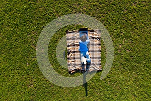 Happy young man with laptop relaxing on the grass, view from above