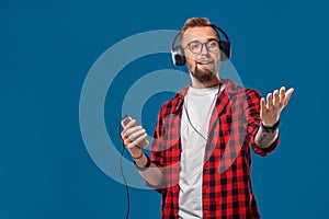 Happy young man listening to music with headphones. Handsome smiling guy in checkered shirt dancing with headphones.