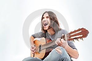 Happy young man with long hair playing guitar and singing