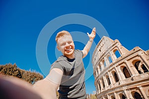 Happy young man making selfie in front of Colosseum in Rome, Italy. Concept travel trip