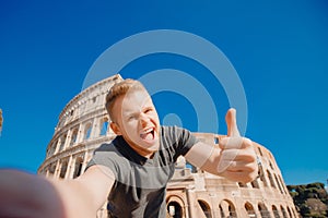Happy young man making selfie thumb up sign in front of Colosseum in Rome, Italy. Concept travel trip