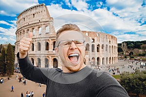 Happy young man making selfie thumb up sign in front of Colosseum in Rome, Italy. Concept travel trip