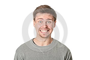 Happy young man with manic expression, on gray background