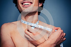 Happy young man is measuring his neck