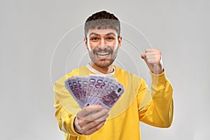 Happy young man with money celebrating success