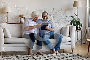 Happy young man and old father using digital tablet.