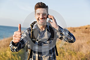 Happy young man outside in free alternative vacation camping talking by mobile phone