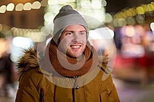 Happy young man over christmas lights in winter