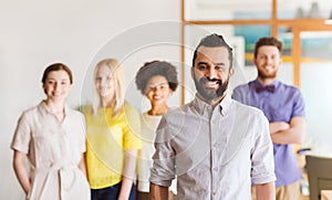 Happy young man over creative team in office