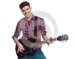 Happy young man playing his electric guitar and smiling