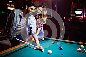 Happy young man playing snooker with his girlfriend. Happy loving couple.