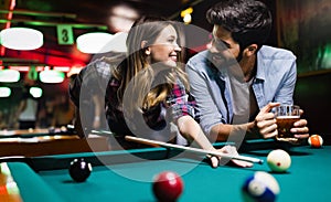 Happy young man playing snooker with his girlfriend. Happy loving couple.