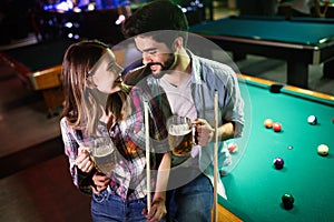 Happy young man playing snooker with his girlfriend. Happy loving couple.