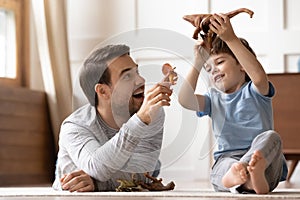 Happy young man playing toys with joyful small schoolboy.